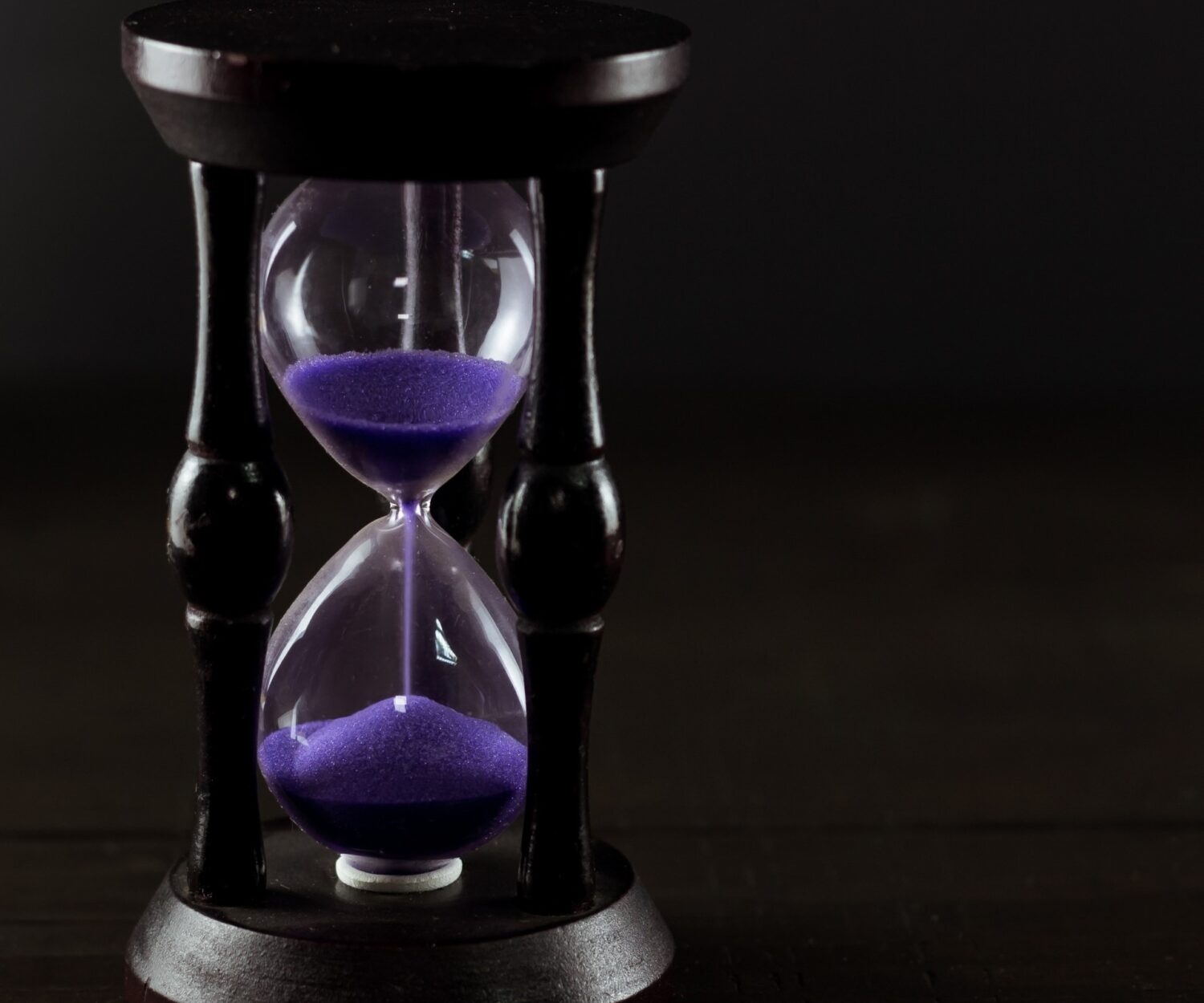 Hourglass with purple sand on office table